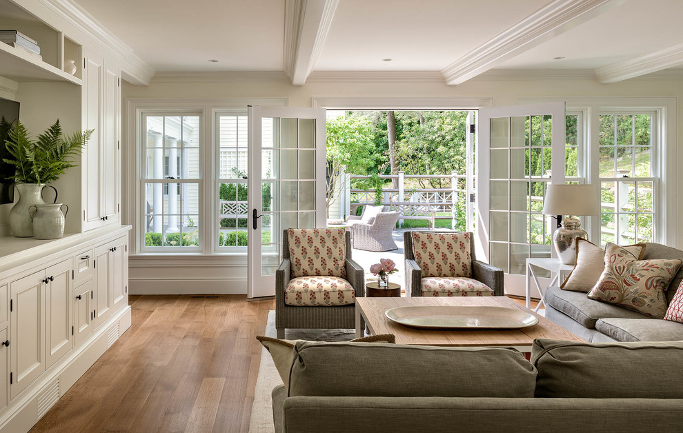 Modelo de sala de estar cerrada clásica renovada grande con paredes blancas, suelo de madera en tonos medios, pared multimedia y suelo marrón