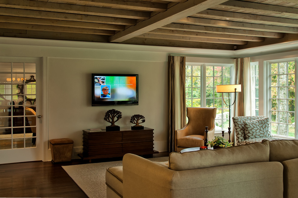 Modelo de sala de estar cerrada de estilo americano pequeña sin chimenea con paredes beige, suelo de madera oscura y televisor colgado en la pared