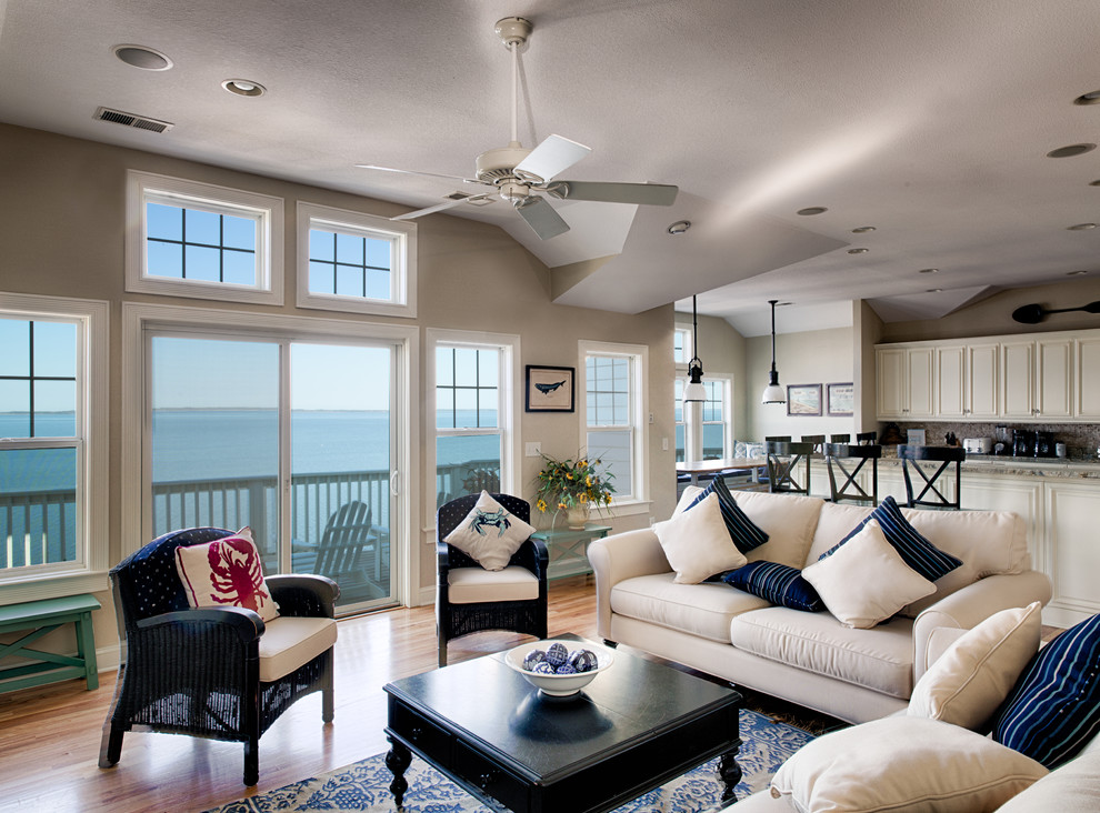 This is an example of a large coastal open plan games room in Other with beige walls, medium hardwood flooring, a standard fireplace, a stone fireplace surround and a wall mounted tv.