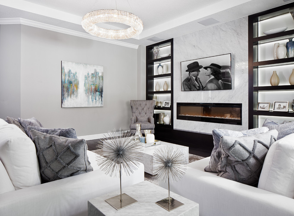 Imagen de sala de estar actual con paredes grises, suelo de madera en tonos medios, marco de chimenea de piedra, televisor colgado en la pared y suelo negro