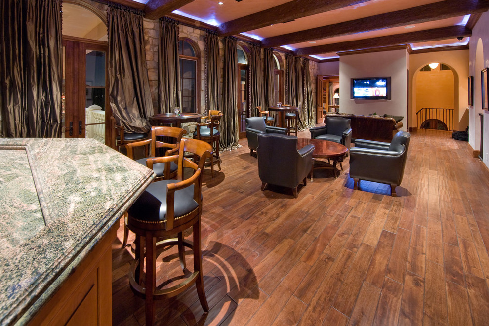 Diseño de sala de estar con barra de bar abierta mediterránea grande sin chimenea con paredes blancas, suelo de madera en tonos medios y televisor colgado en la pared
