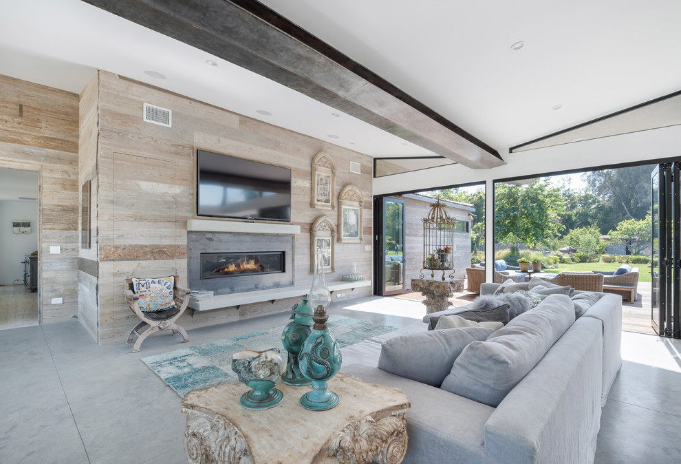 Modelo de sala de estar abierta retro grande con suelo de cemento, chimenea lineal, televisor colgado en la pared, suelo gris y alfombra