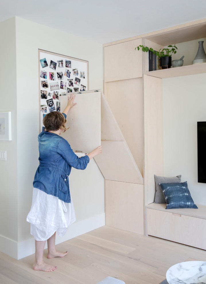 Ejemplo de sala de estar escandinava pequeña con paredes grises, suelo de madera clara y televisor colgado en la pared