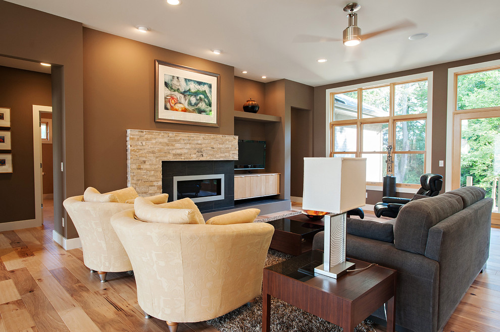 Mittelgroßes, Offenes Modernes Wohnzimmer mit brauner Wandfarbe, hellem Holzboden, Kamin, Kaminumrandung aus Stein und freistehendem TV in Cincinnati