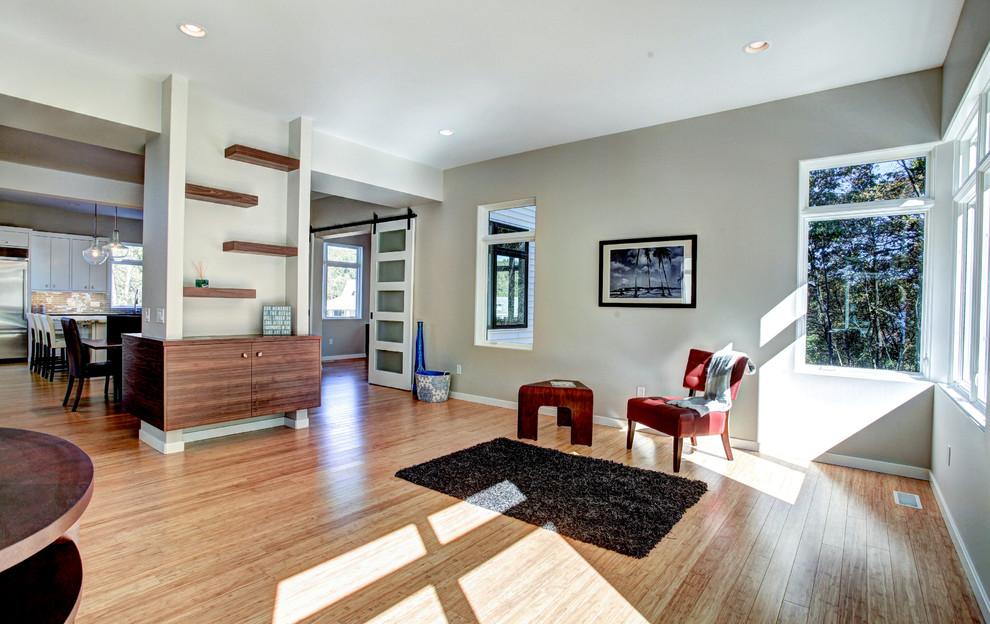 Immagine di un grande soggiorno design aperto con pareti grigie, pavimento in bambù, nessun camino e TV a parete