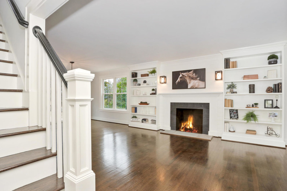 ニューヨークにあるお手頃価格の中くらいなカントリー風のおしゃれなオープンリビング (白い壁、濃色無垢フローリング、標準型暖炉、木材の暖炉まわり、茶色い床) の写真