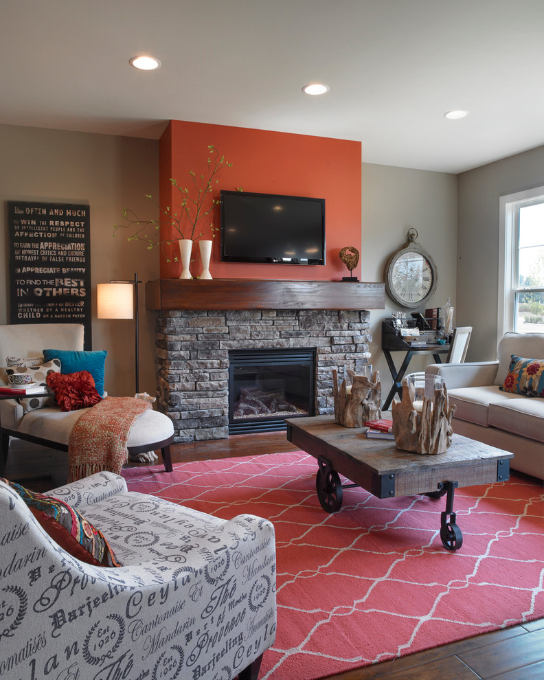 Cette image montre une grande salle de séjour traditionnelle ouverte avec un mur orange, parquet foncé, une cheminée standard, un manteau de cheminée en pierre et un téléviseur fixé au mur.
