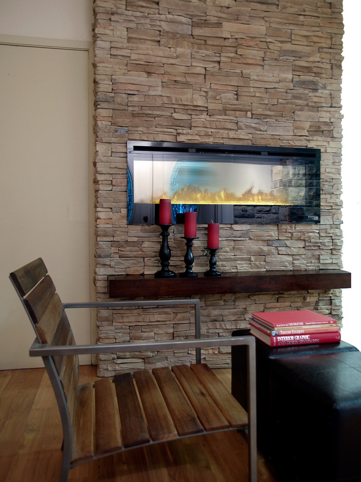 Imagen de sala de estar clásica renovada sin televisor con paredes beige, suelo de madera en tonos medios, todas las chimeneas y marco de chimenea de piedra