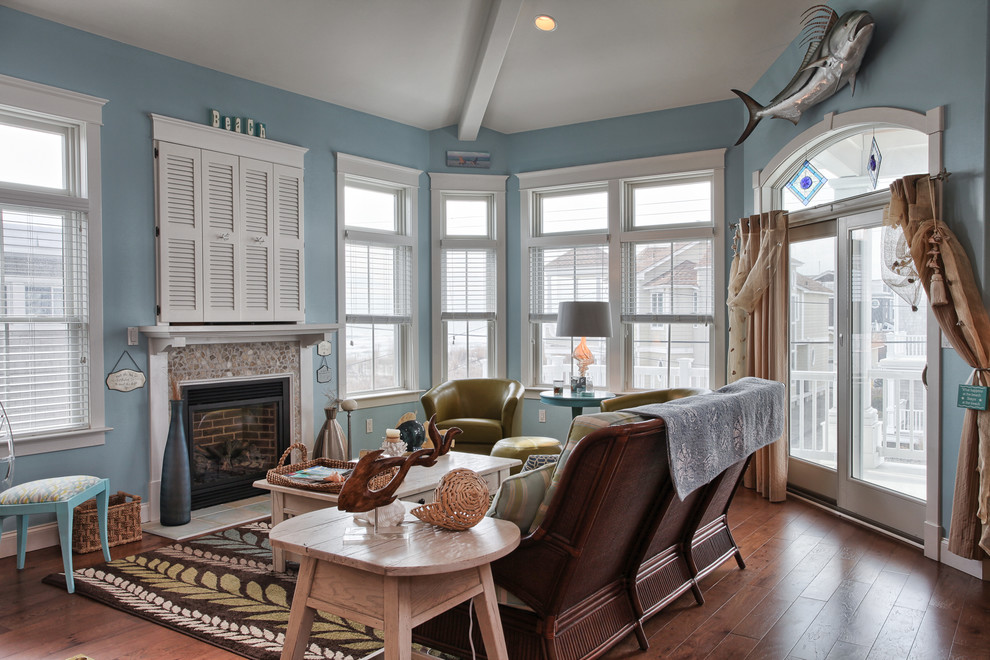 Diseño de sala de estar costera con paredes azules, televisor retractable y marco de chimenea de baldosas y/o azulejos