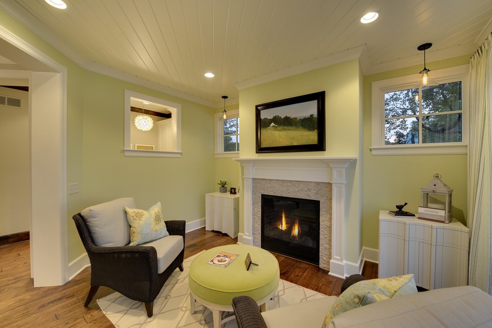 Immagine di un soggiorno classico con pareti verdi, pavimento in legno massello medio, camino classico e TV a parete
