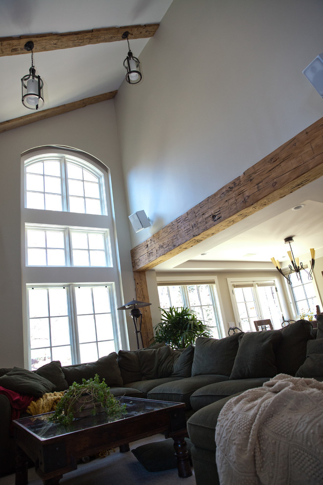 Cette image montre une grande salle de séjour bohème ouverte avec un mur beige, un sol en bois brun, une cheminée d'angle, un manteau de cheminée en plâtre, un téléviseur indépendant et un sol marron.