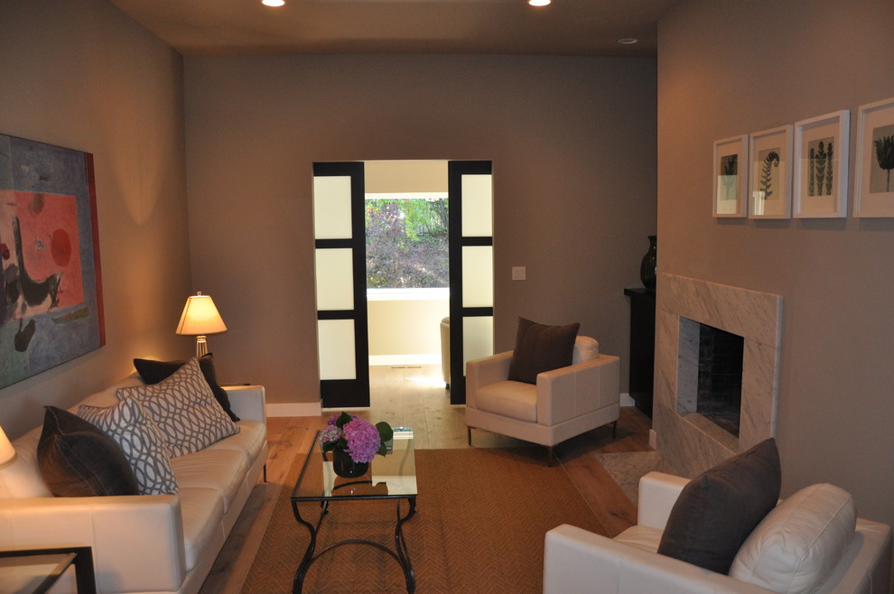 Свежая идея для дизайна: изолированная гостиная комната в стиле ретро с серыми стенами, паркетным полом среднего тона, стандартным камином, фасадом камина из камня и телевизором на стене - отличное фото интерьера