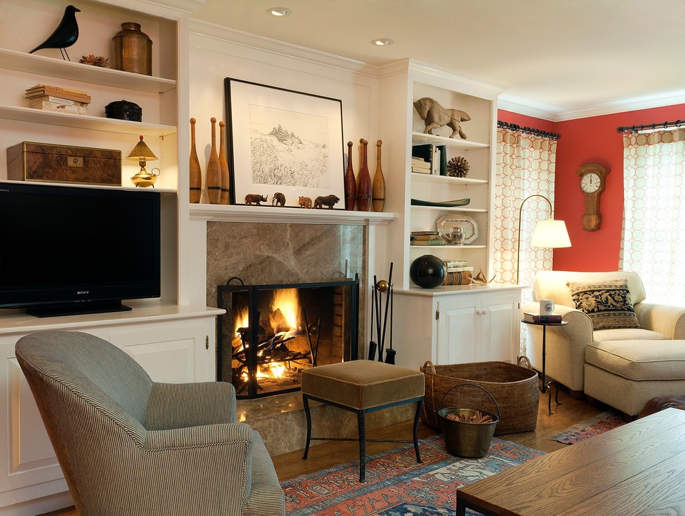 Imagen de sala de estar cerrada actual de tamaño medio con paredes rojas, suelo de madera en tonos medios, todas las chimeneas y televisor independiente