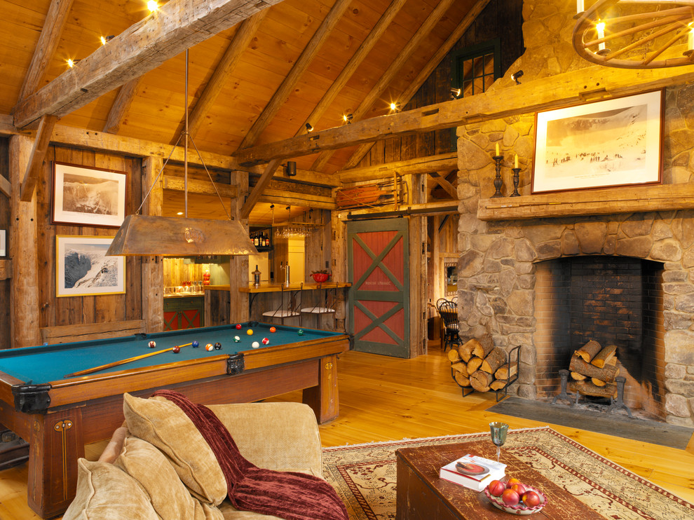 Cette image montre une salle de séjour rustique avec un sol en bois brun, une cheminée standard, aucun téléviseur et un manteau de cheminée en pierre.