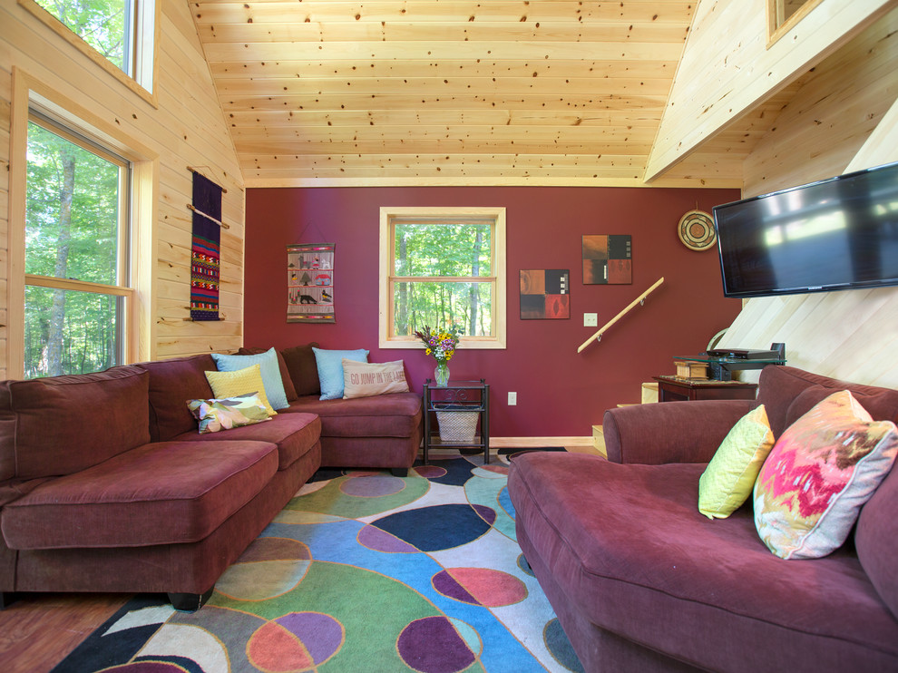 Mountain style open concept medium tone wood floor family room photo in Omaha with red walls, no fireplace and a wall-mounted tv