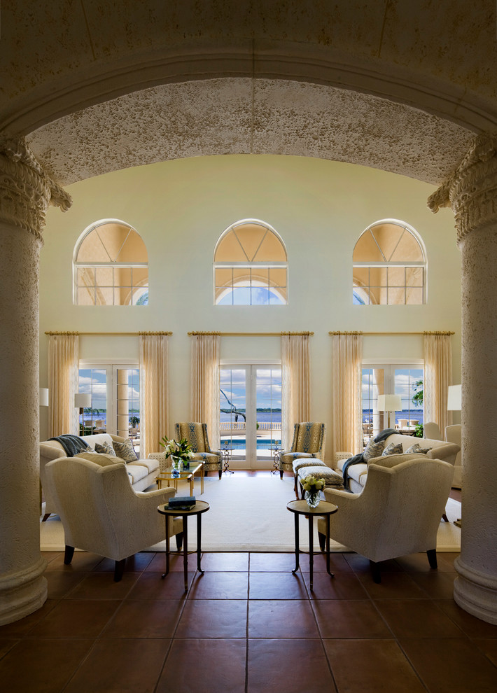 Imagen de sala de estar abierta mediterránea grande sin chimenea con paredes beige, suelo de baldosas de terracota y suelo rojo