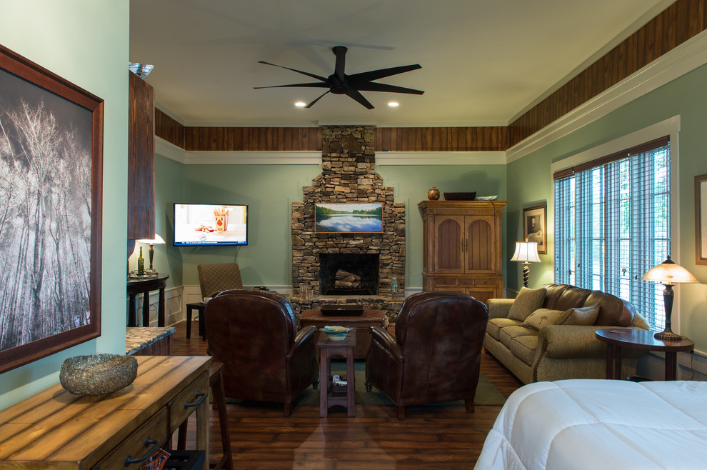Exemple d'une salle de séjour montagne de taille moyenne et ouverte avec un mur vert, une cheminée standard, un manteau de cheminée en pierre, un téléviseur fixé au mur et un sol en bois brun.