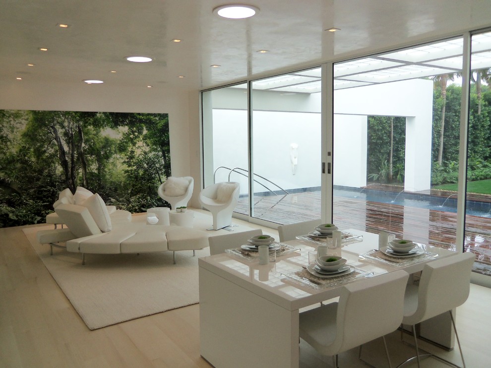 Réalisation d'une très grande salle de séjour minimaliste ouverte avec un mur blanc, parquet clair et un téléviseur fixé au mur.