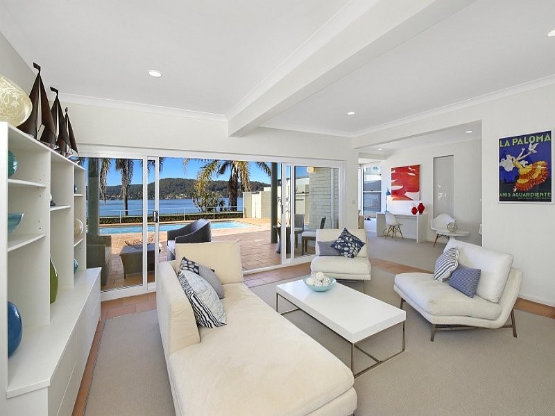 Imagen de sala de estar abierta costera de tamaño medio sin chimenea y televisor con paredes blancas, suelo de baldosas de terracota y suelo rojo