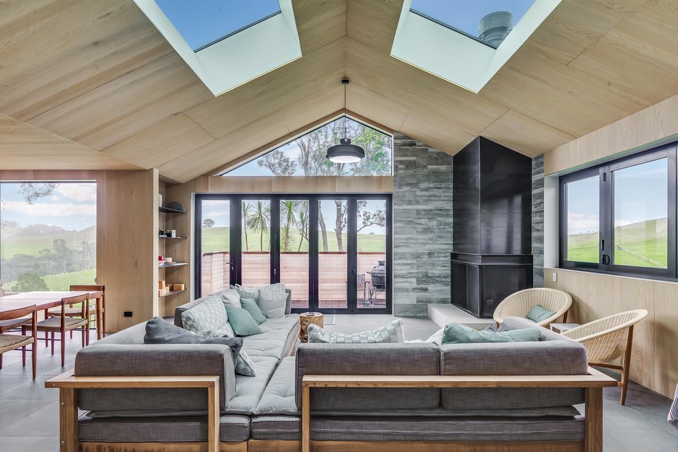 Offenes Skandinavisches Wohnzimmer mit beiger Wandfarbe, Eckkamin, Kaminumrandung aus Metall und grauem Boden in Auckland