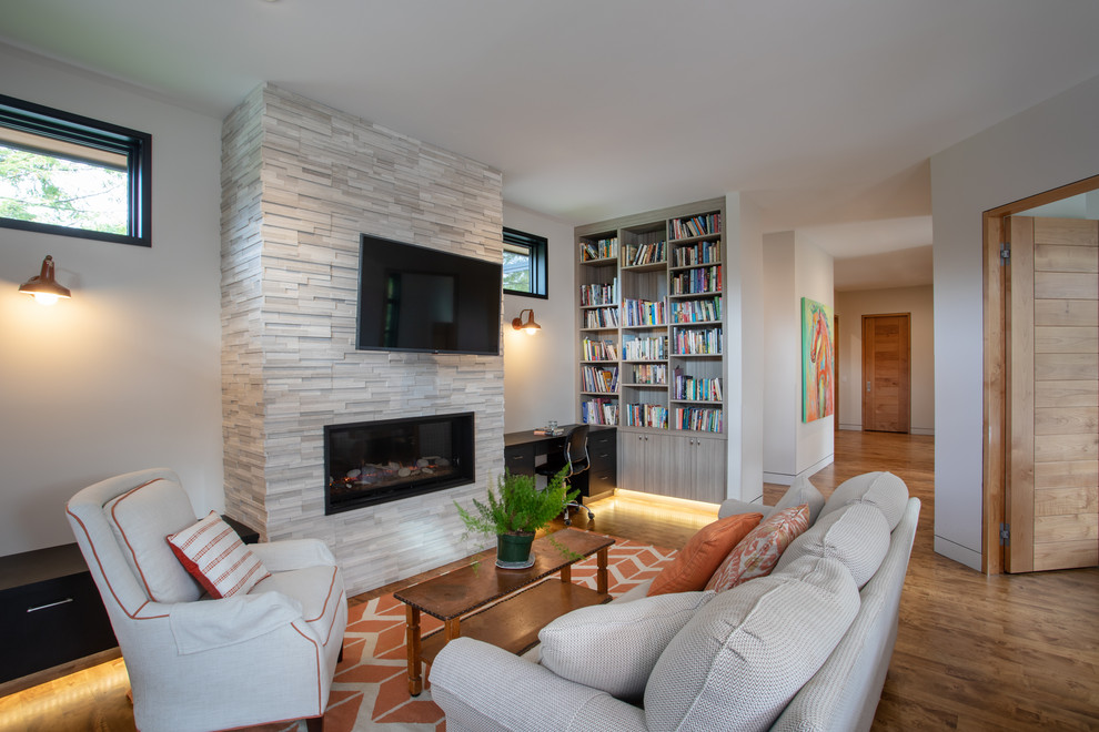 Idée de décoration pour une salle de séjour minimaliste de taille moyenne et fermée avec un mur blanc, un sol en bois brun, une cheminée ribbon, un manteau de cheminée en pierre, un téléviseur fixé au mur et un sol marron.