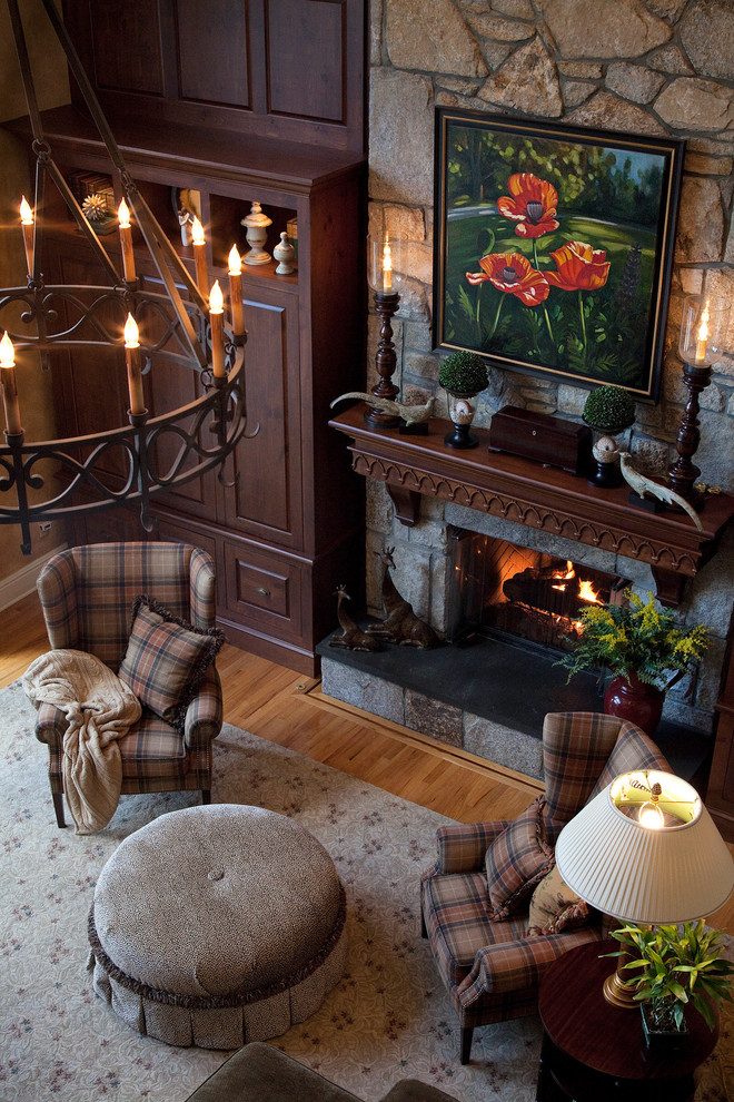 Imagen de sala de estar abierta tradicional extra grande con paredes beige, suelo de madera clara, todas las chimeneas, marco de chimenea de piedra y televisor retractable
