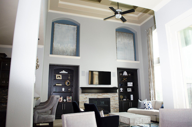Стильный дизайн: открытая гостиная комната среднего размера в современном стиле с серыми стенами, стандартным камином, фасадом камина из камня и телевизором на стене - последний тренд