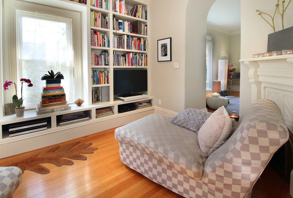 Ejemplo de sala de estar con biblioteca cerrada contemporánea de tamaño medio sin chimenea con paredes grises, suelo de madera clara, televisor independiente y suelo marrón
