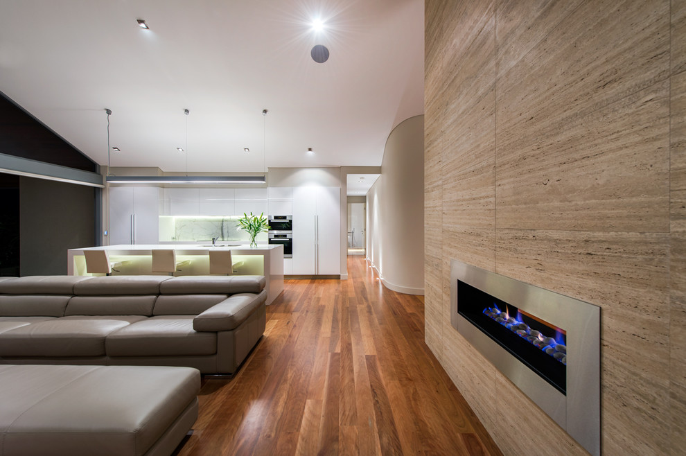 Cette image montre une très grande salle de séjour design ouverte avec un mur beige, un sol en bois brun, une cheminée double-face et un manteau de cheminée en métal.
