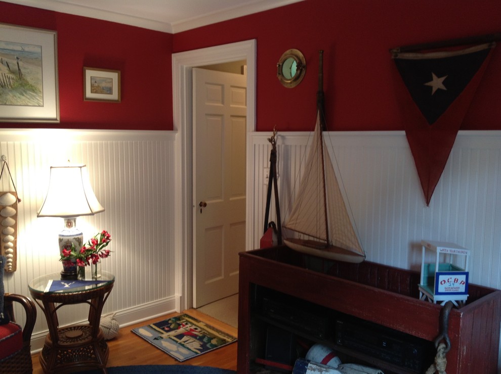 Aménagement d'une petite salle de séjour bord de mer fermée avec un mur rouge, un sol en bois brun, aucune cheminée et aucun téléviseur.