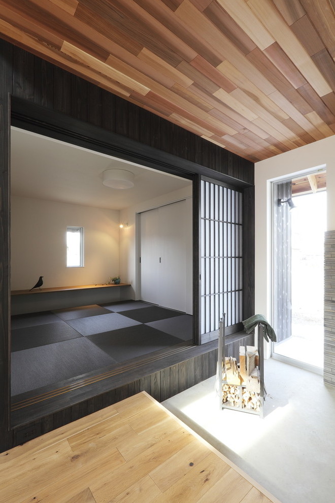 Imagen de sala de estar abierta retro de tamaño medio con paredes negras, tatami, televisor colgado en la pared y suelo negro