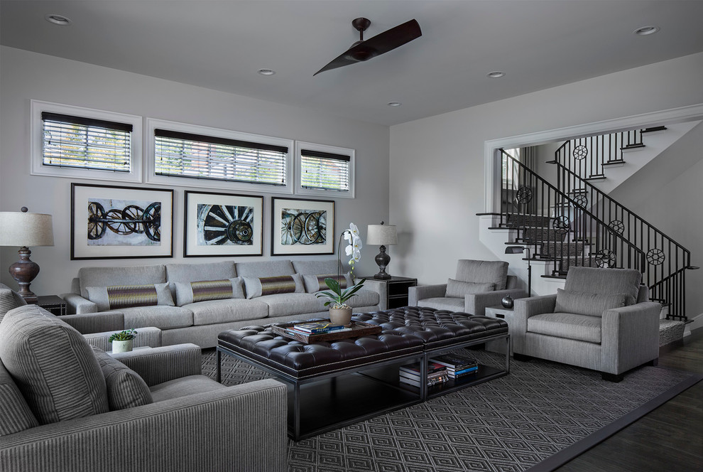 Modelo de sala de estar abierta tradicional renovada grande con paredes grises, suelo de madera oscura y televisor colgado en la pared