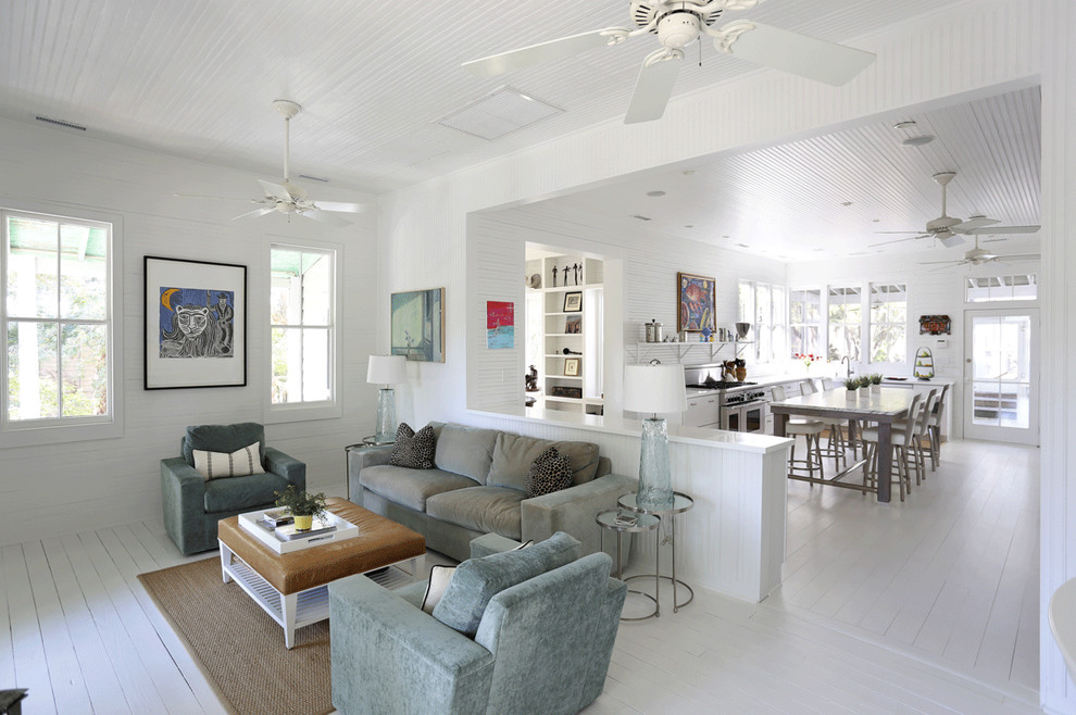 Offenes Maritimes Wohnzimmer mit weißer Wandfarbe, gebeiztem Holzboden und weißem Boden in Charleston