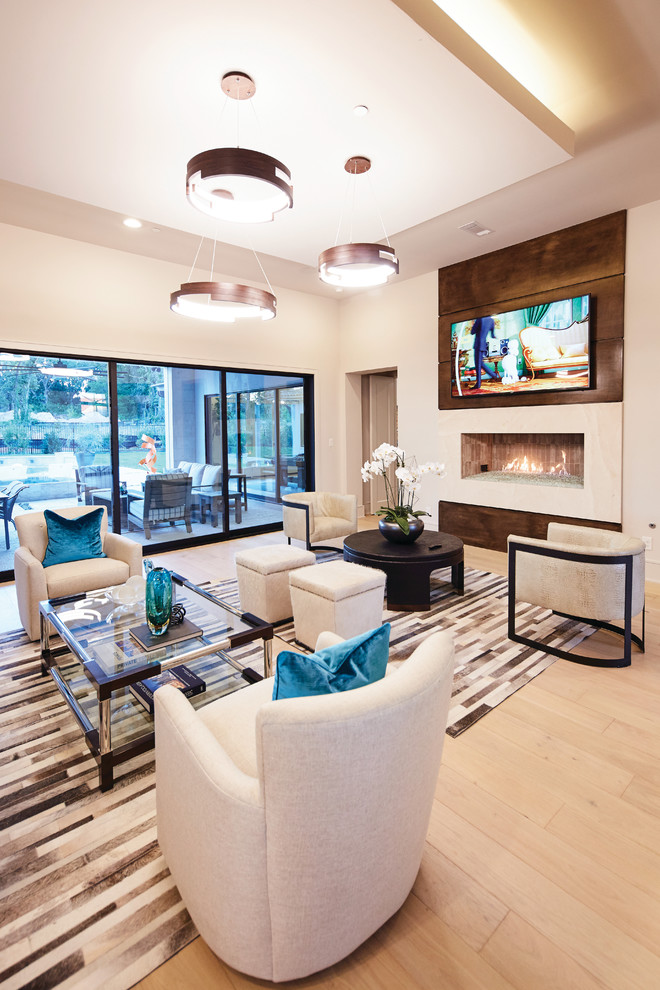 Imagen de sala de estar abierta contemporánea de tamaño medio con paredes blancas, suelo de madera clara, chimenea lineal, marco de chimenea de piedra, televisor colgado en la pared y suelo marrón