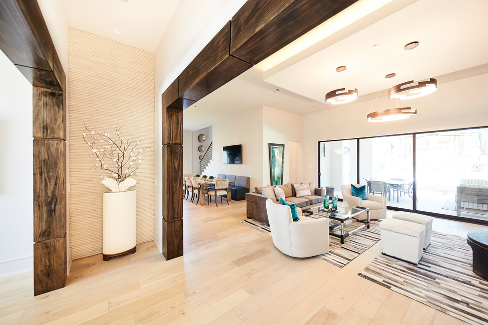 Mittelgroßes, Offenes Modernes Wohnzimmer mit weißer Wandfarbe, hellem Holzboden, Gaskamin, Kaminumrandung aus Stein, TV-Wand und braunem Boden in Dallas