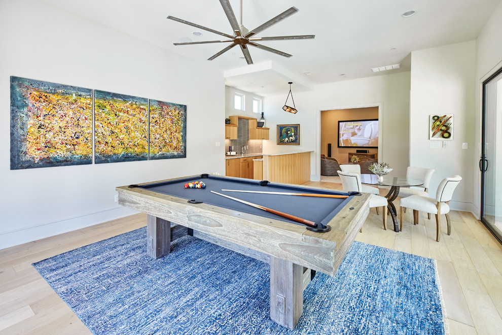 Diseño de sala de juegos en casa cerrada contemporánea de tamaño medio sin chimenea con paredes blancas, suelo de madera clara, televisor colgado en la pared y suelo marrón