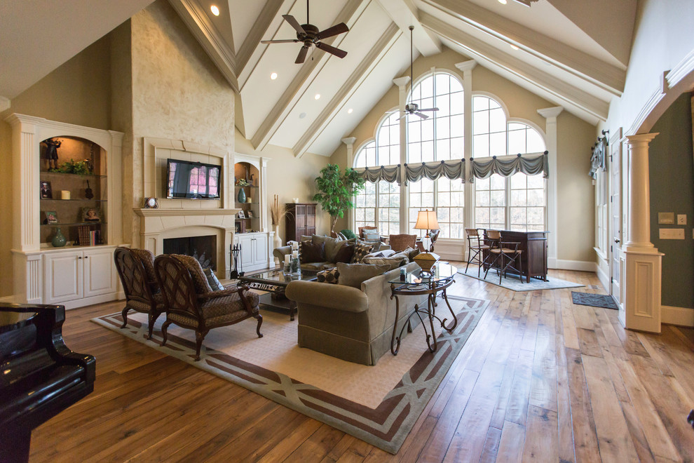 Example of a mid-sized transitional open concept medium tone wood floor family room design in Raleigh with beige walls, a standard fireplace, a plaster fireplace and a wall-mounted tv