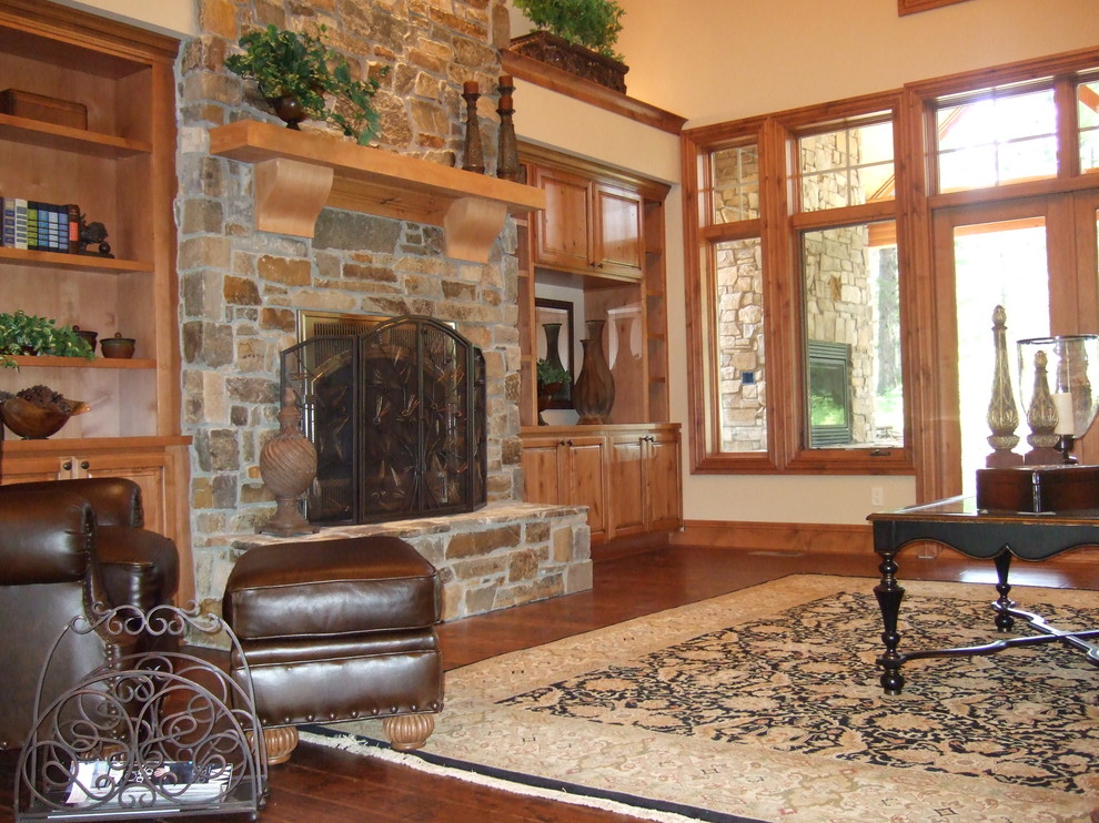 Example of a mid-sized classic enclosed dark wood floor and brown floor family room design in Seattle with beige walls, a standard fireplace, a stone fireplace and no tv