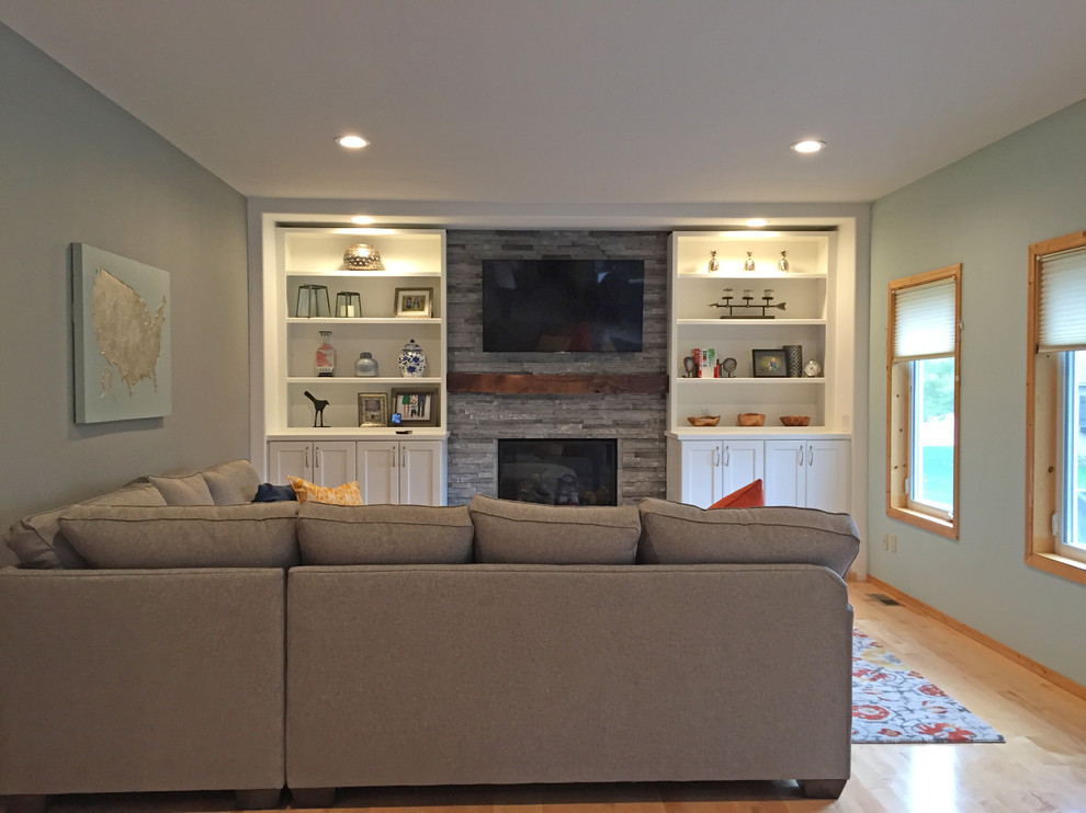 Ejemplo de sala de estar tradicional renovada pequeña con paredes grises, suelo de madera clara, todas las chimeneas, marco de chimenea de piedra y televisor colgado en la pared