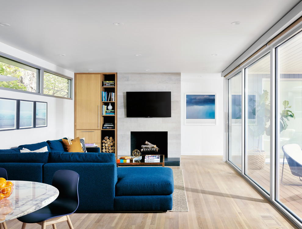 На фото: открытая гостиная комната в современном стиле с белыми стенами, светлым паркетным полом, стандартным камином и телевизором на стене