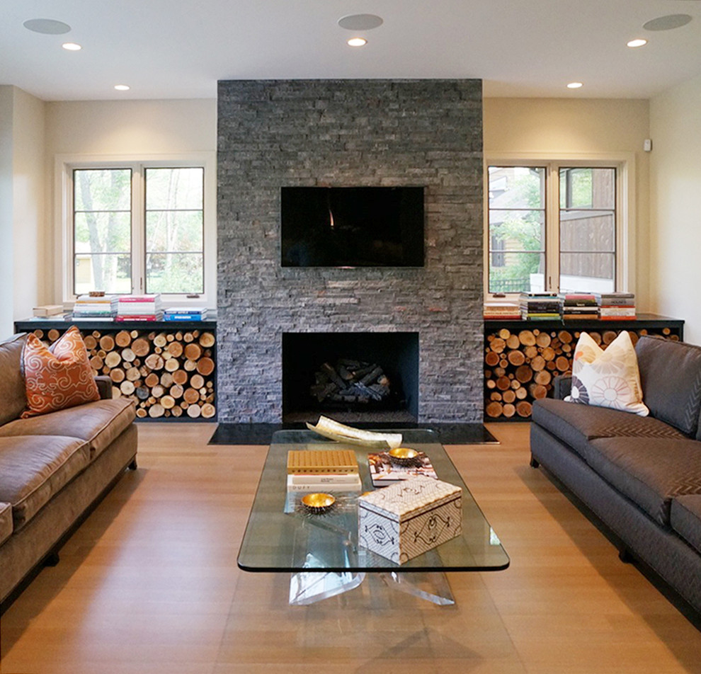 Imagen de sala de estar abierta tradicional renovada grande sin chimenea con paredes beige, suelo de madera clara, marco de chimenea de piedra y televisor colgado en la pared