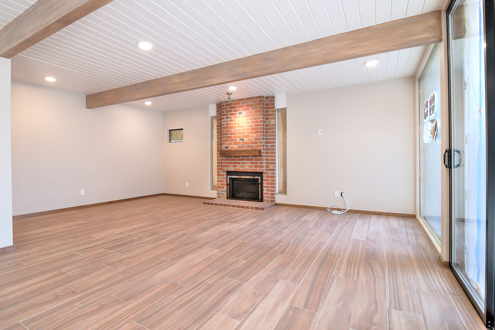Cette photo montre une salle de séjour rétro ouverte avec un mur blanc, un sol en carrelage de céramique, une cheminée standard, un manteau de cheminée en brique et un sol marron.