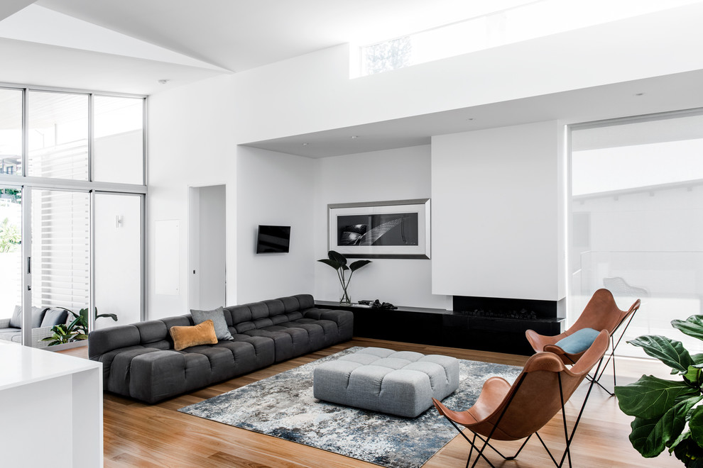 Photo of a coastal open plan games room in Sunshine Coast with white walls, light hardwood flooring, a ribbon fireplace, beige floors and a wall mounted tv.