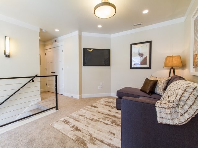 Ejemplo de sala de estar tipo loft clásica renovada pequeña con paredes beige, moqueta y televisor colgado en la pared