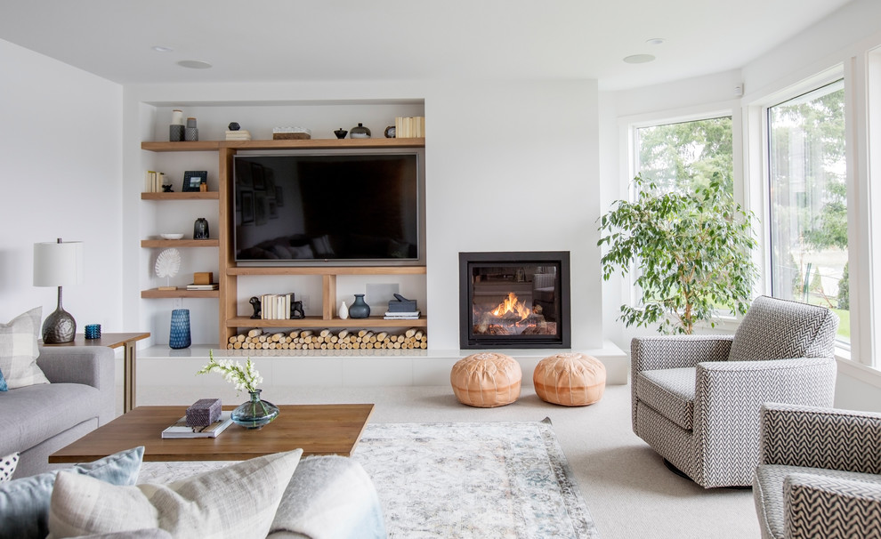 Источник вдохновения для домашнего уюта: гостиная комната в современном стиле с белыми стенами, ковровым покрытием, стандартным камином, телевизором на стене и серым полом