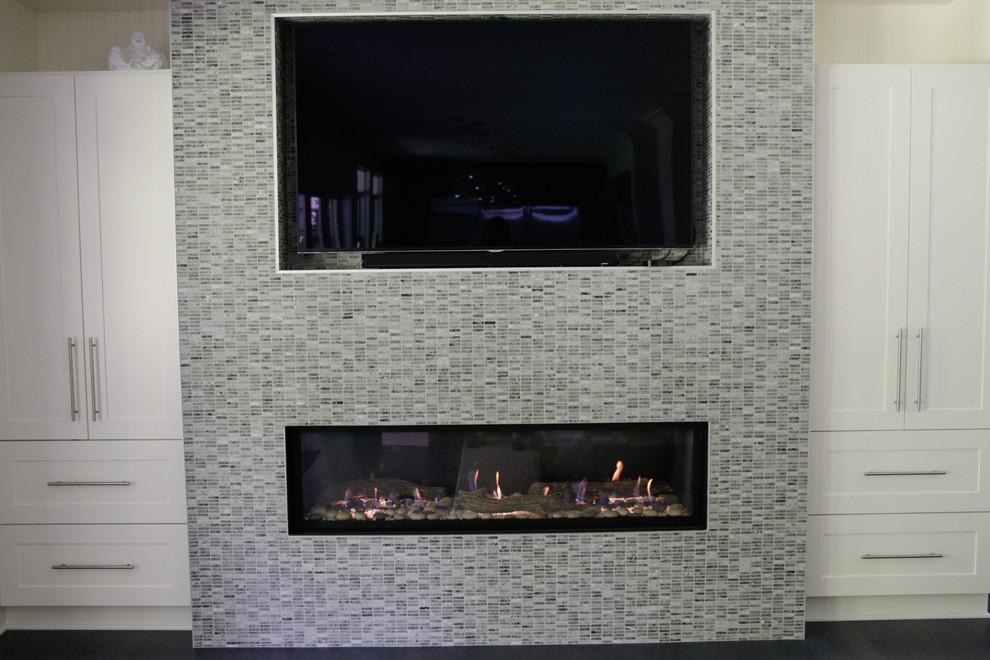 Esempio di un grande soggiorno minimal con pareti grigie, parquet scuro, camino classico, cornice del camino in pietra e TV a parete