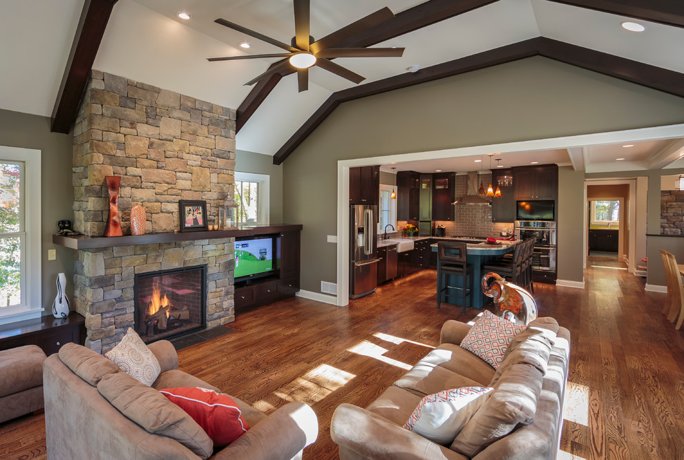 Large elegant open concept medium tone wood floor family room photo in Minneapolis with green walls, a standard fireplace, a stone fireplace and a media wall