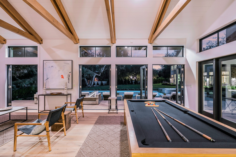 Huge trendy open concept light wood floor and brown floor game room photo in Los Angeles with white walls and no tv
