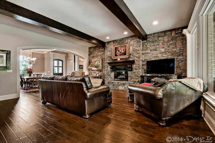Photo of a medium sized rustic open plan games room in Little Rock with dark hardwood flooring, a standard fireplace, a stone fireplace surround, a freestanding tv, multi-coloured walls and brown floors.