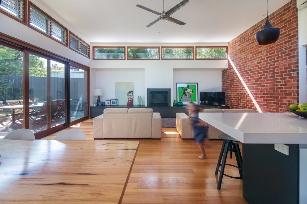 Large contemporary open plan games room in Melbourne with white walls, medium hardwood flooring, a standard fireplace, a plastered fireplace surround and a freestanding tv.